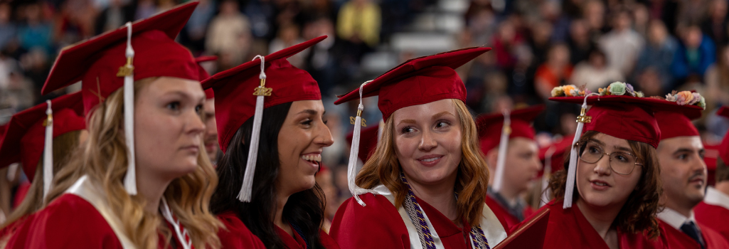 Four SVSU graduates talking and laughing at their graduation.